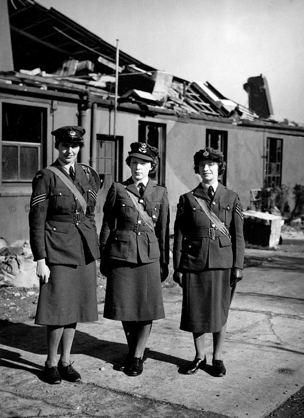 Sergeant Joan E Mortimer Flight Officer Elspeth C Henderson and Sergeant Helen E Turner recipients of the Military Medal for gallantry standing outside damaged