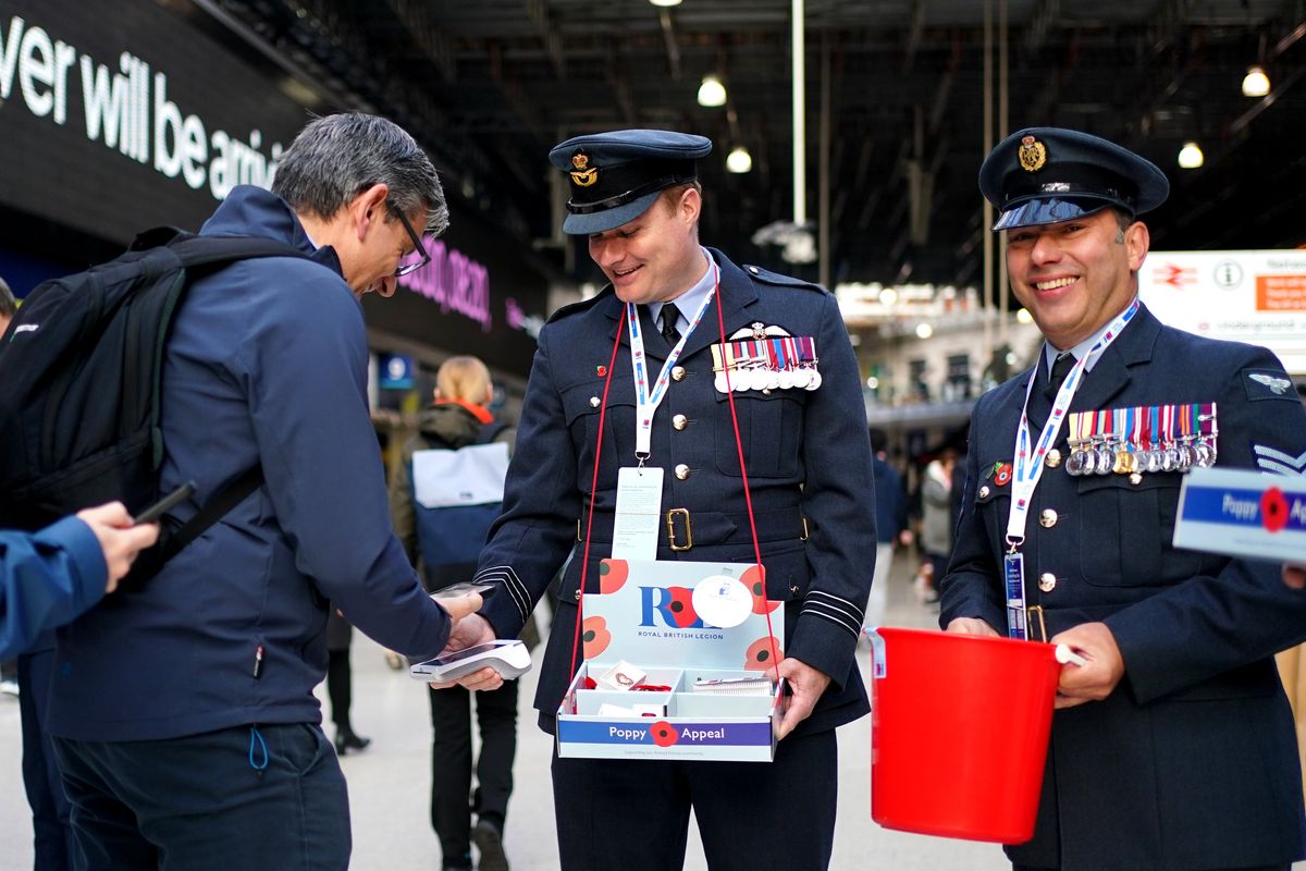 Serving military personnel hand out poppies and collect donations at the launch of the Royal British Legion's annual London Poppy Day at Waterloo Station