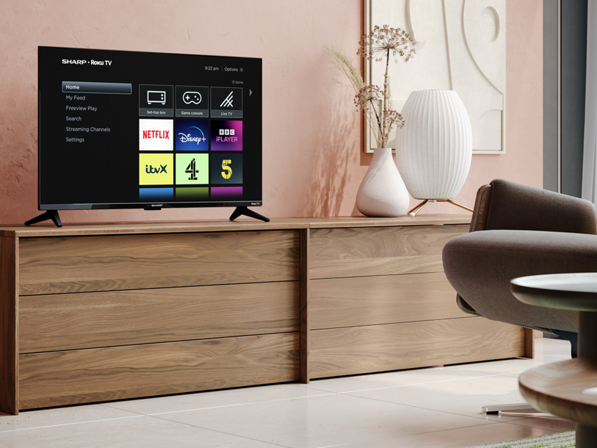 Sharp TV pictured in the corner of a living room with a Roku TV running its software