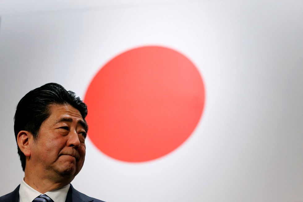 Shinzo Abe stands in front of Japan's national flag