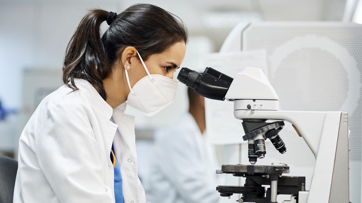 Side view of female doctor using microscope during research in laboratory