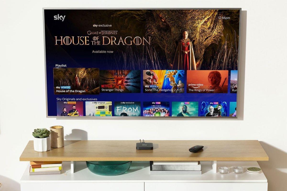 sky stream box pictured on a media unit with the flatscreen showing sky tv content on-screen