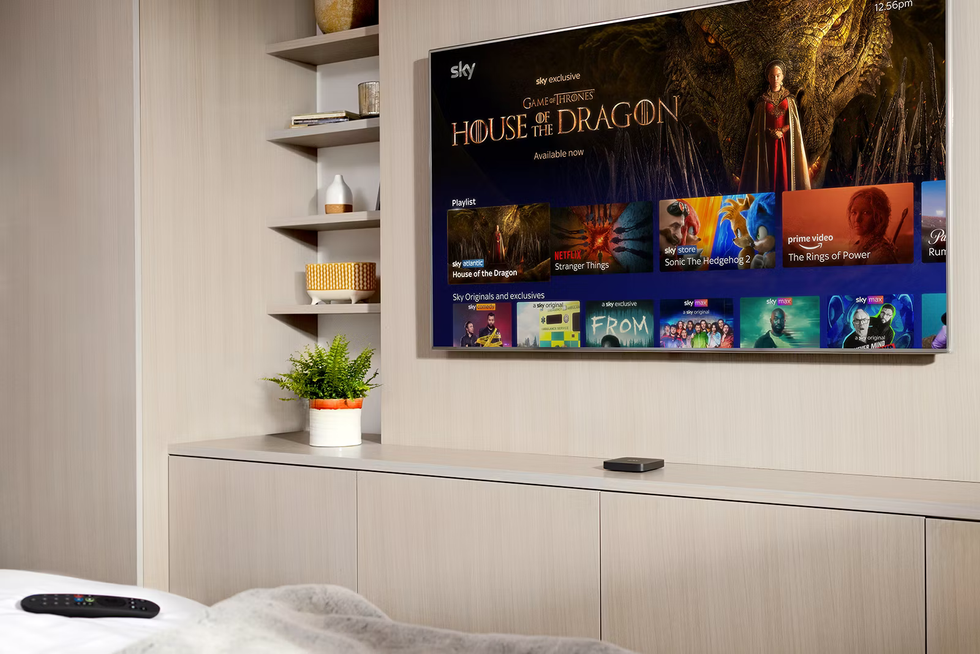 sky stream box pictured on an entertainment unit with a flatscreen tv above and a redesigned remote control on the bed