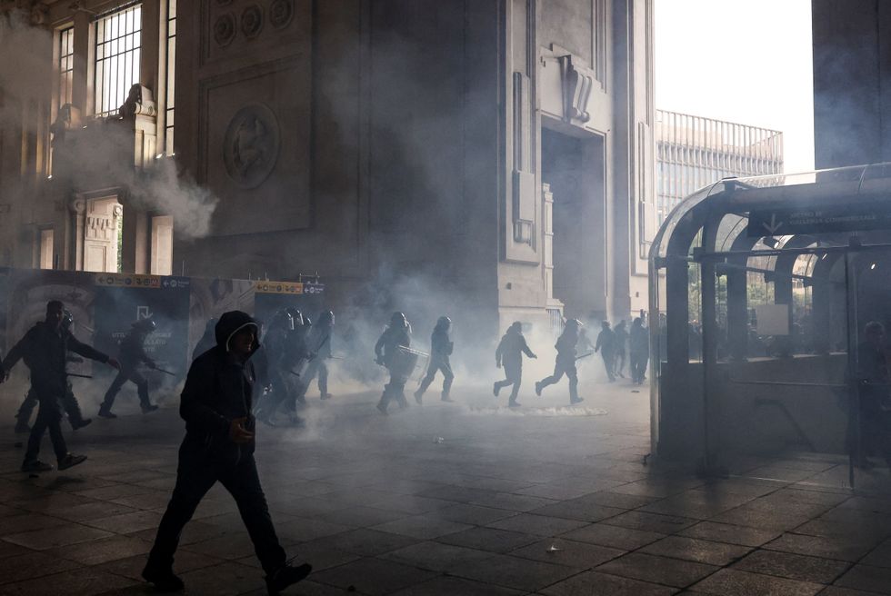 Smoke fills the air inside Milano Centrale as riot police rush to beat back activists