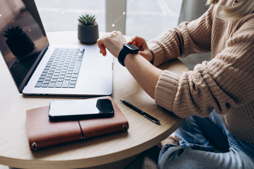 Someone checking their watch by a laptop