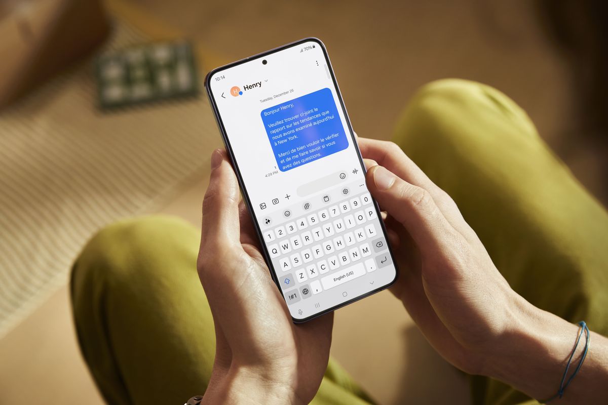 someone holds a galaxy s24 that shows a text message translated using on-device ai