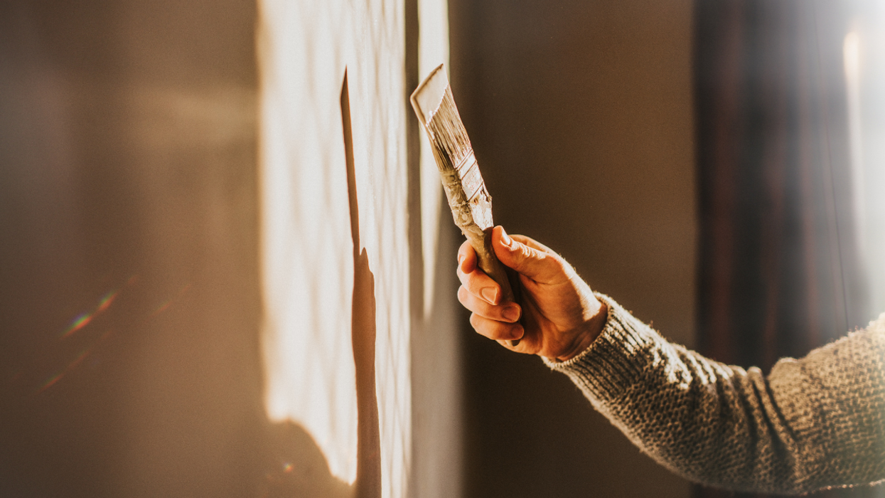 Someone using a brush to paint a wall