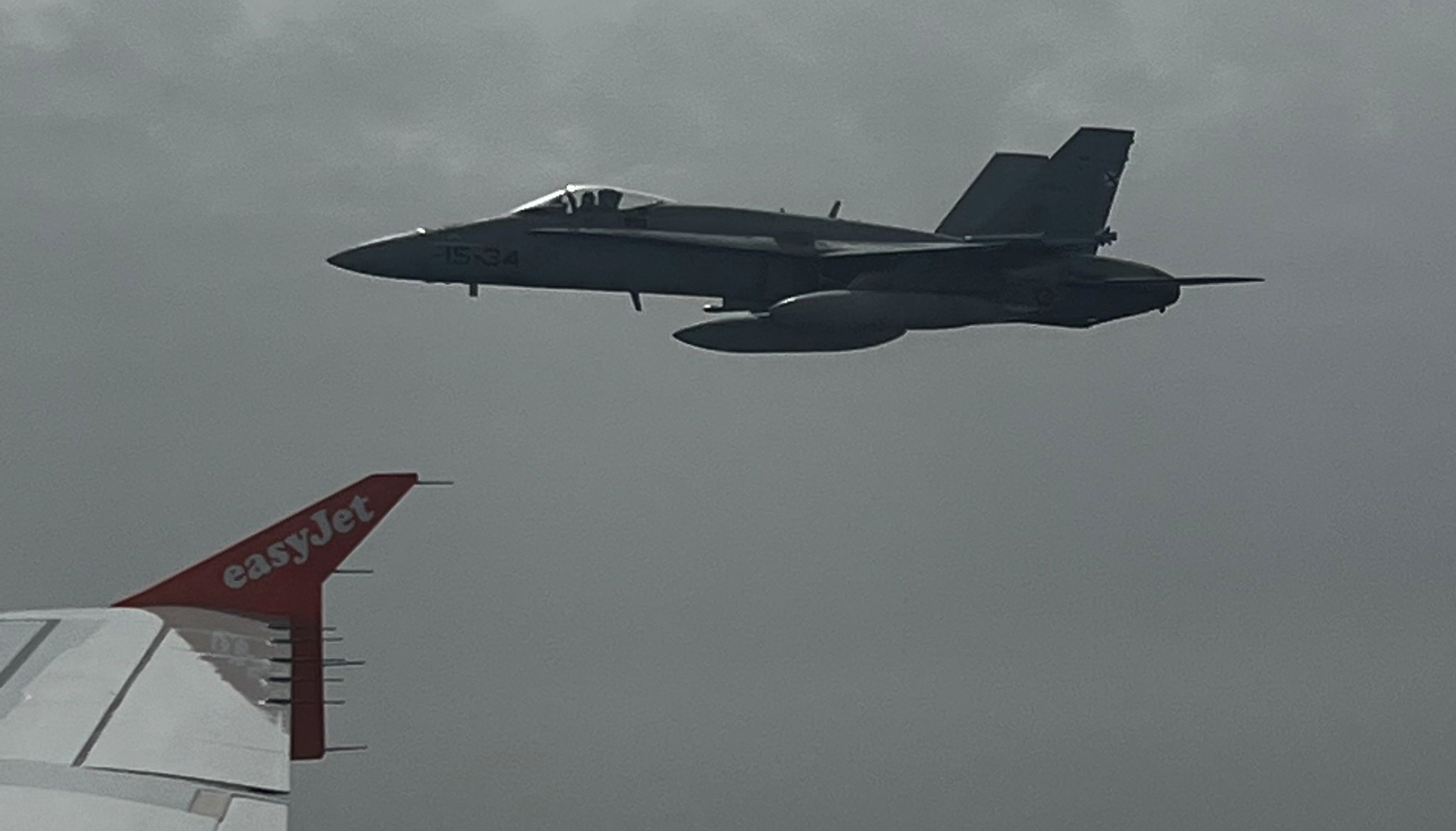 Spanish F-18 jet fighter, seen through plane window, escorts the Easyjet flight