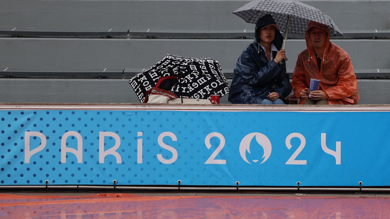 Spectators cover themselves from the rain