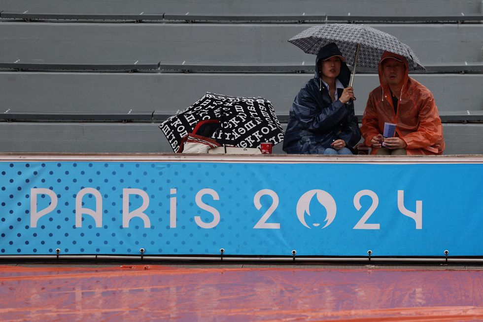 Spectators cover themselves from the rain