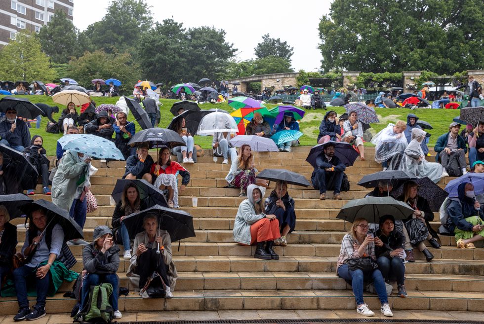 Spectators shelter from the rain on The Hill as they watch the Centre Court action on the large screen on day two of Wimbledon at The All England Lawn Tennis and Croquet Club, Wimbledon
