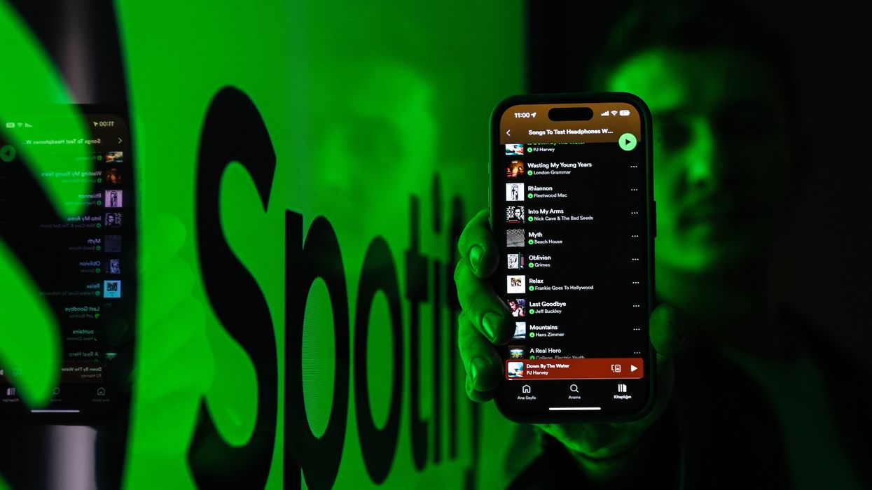 Spotify app open on phone being held by man with logo in the background