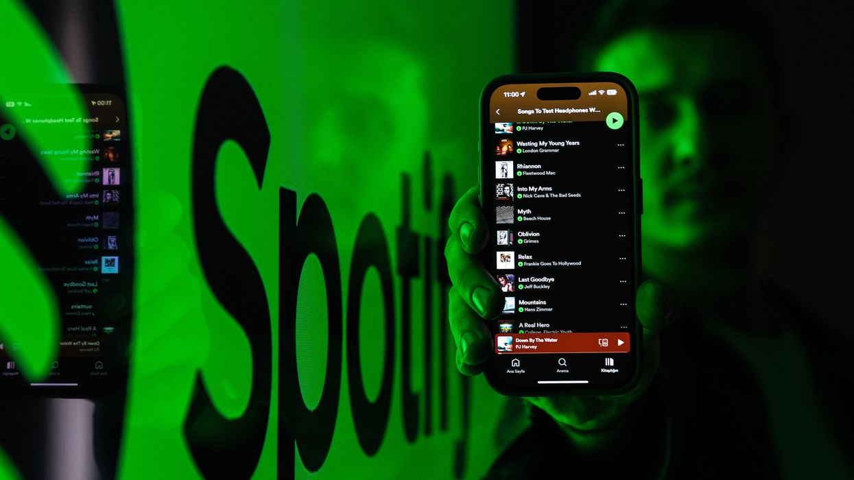 Spotify app open on phone being held by man with logo in the background