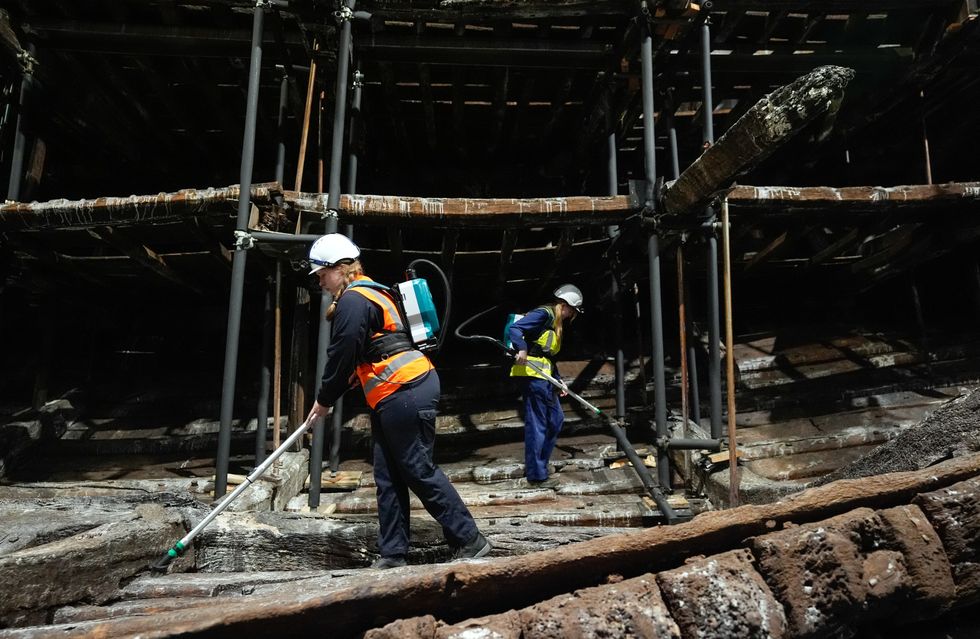 Staff painstakingly clean the wreck of the Tudor warship in its dry dock