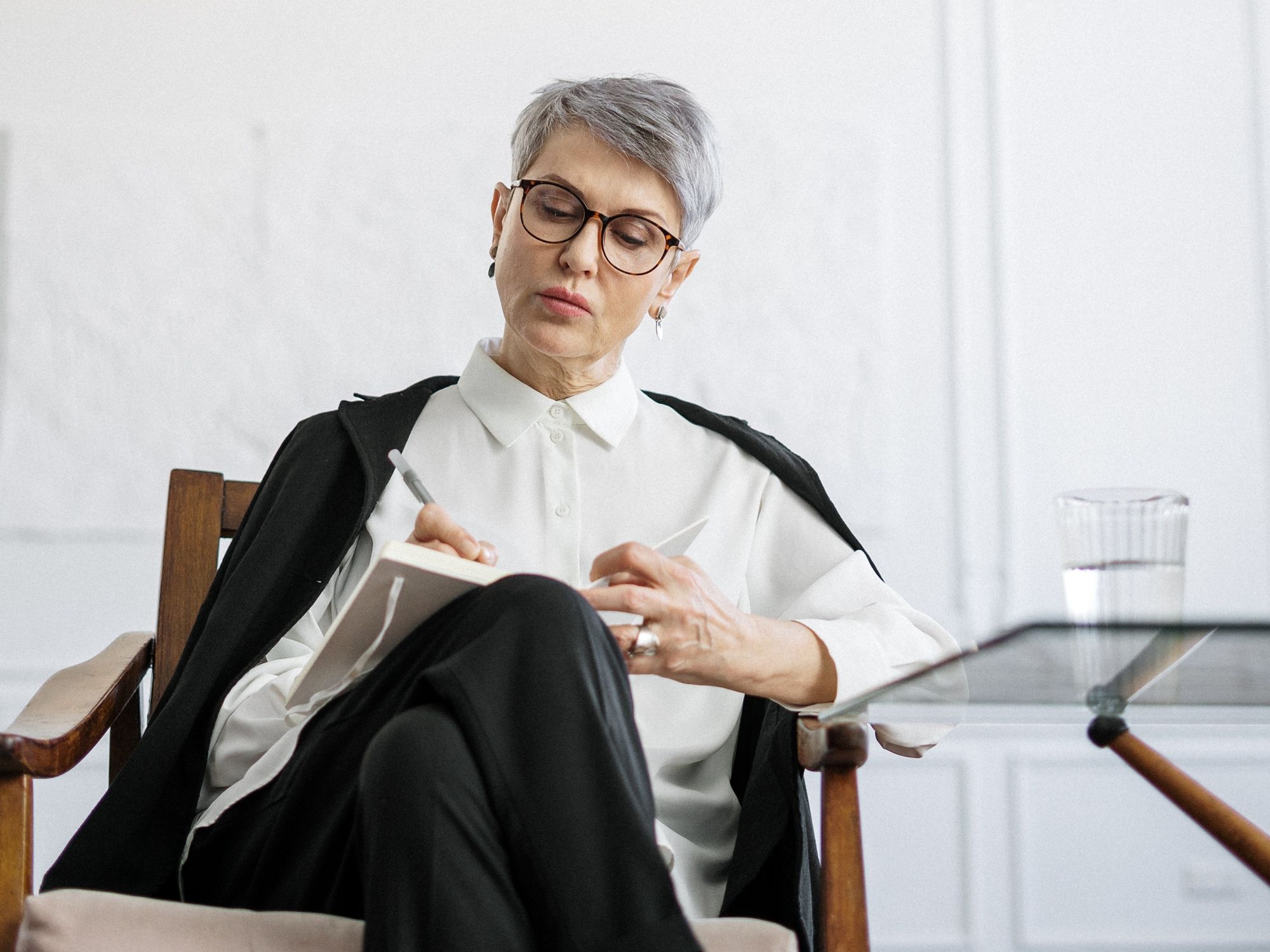State pension age woman sitting on a chair while writing in notepad