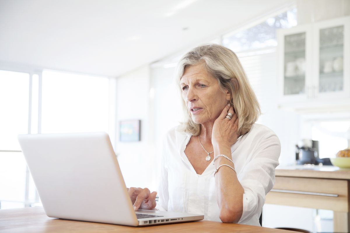 State pensioner looks worried while looking at laptop