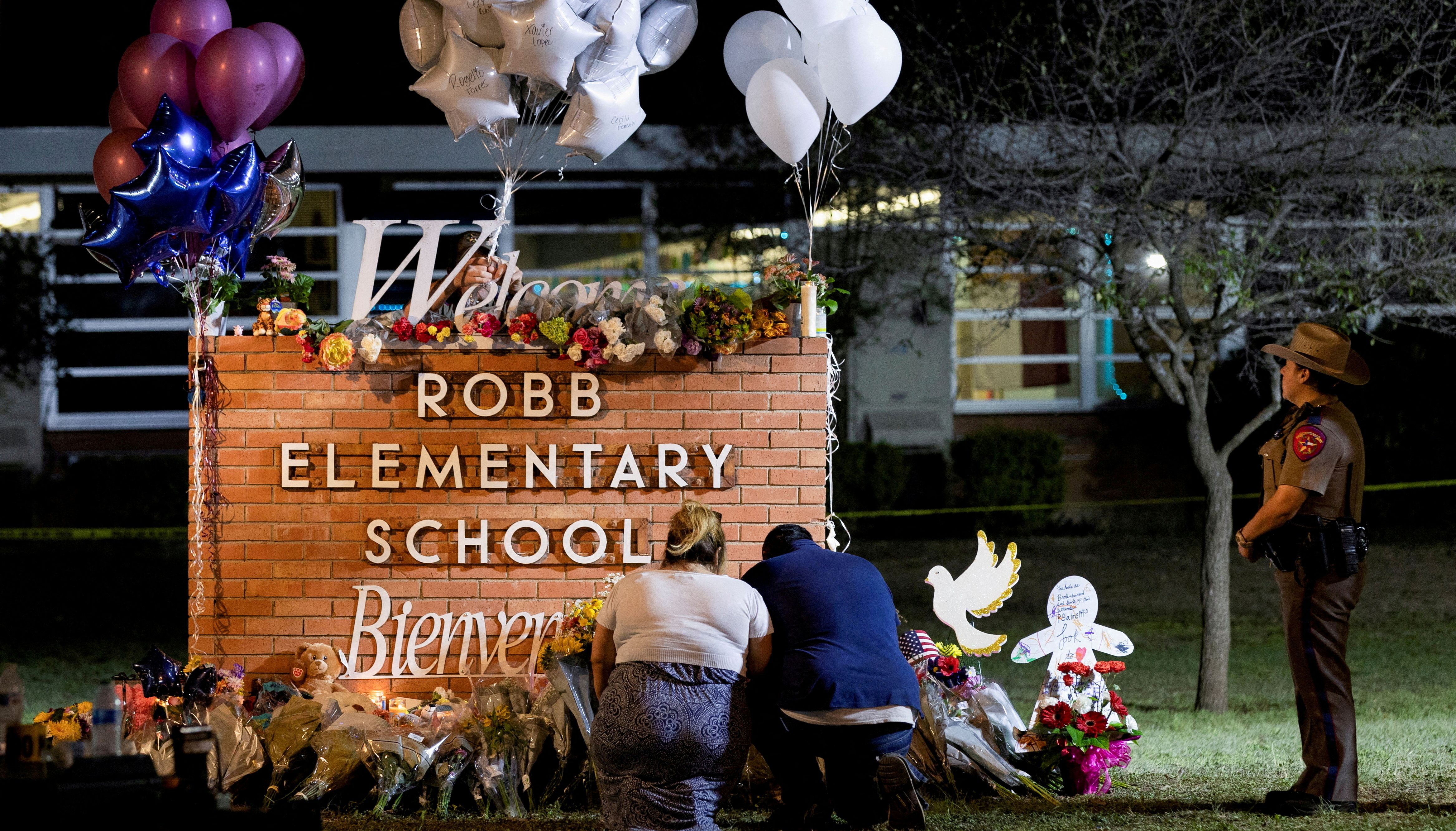 Stephanie and Michael Chavez of San Antonio pay their respects at a makeshift memorial outside Robb Elementary School, the site of a mass shooting, in Uvalde, Texas.