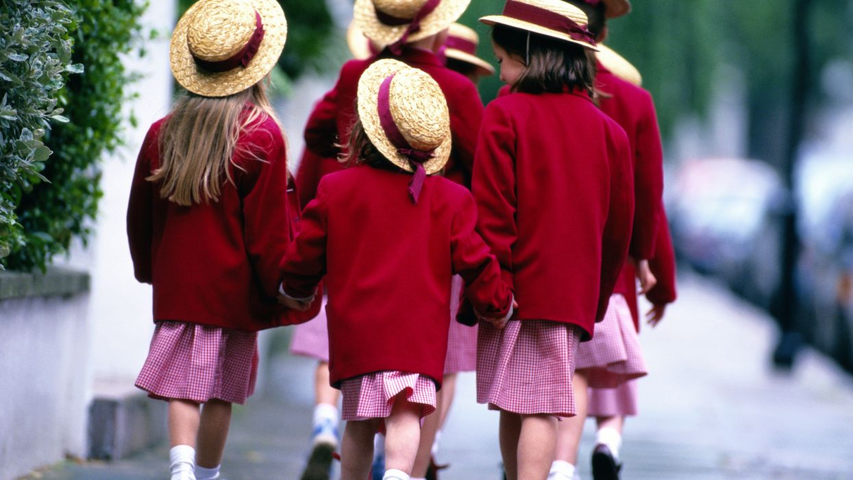 Stock image of children walking to school in red school uniform
