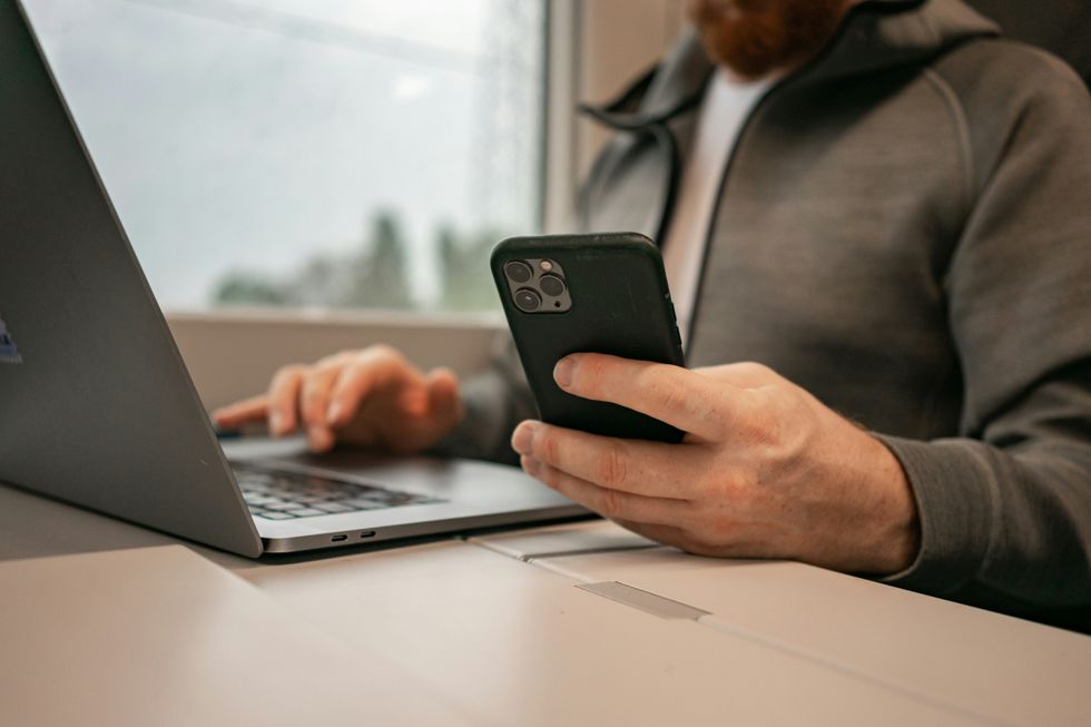 Stock image of someone holding their mobile and working from laptop
