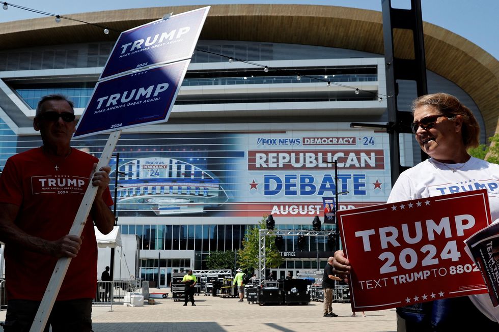 Supporters of Republican presidential candidate and former U.S. President Donald Trump, who is expected to skip the first primary debate of the 2024 campaign against his fellow Republican candidates, walk around the arena with Trump campaign signs the day before the debate in Milwaukee, Wisconsin