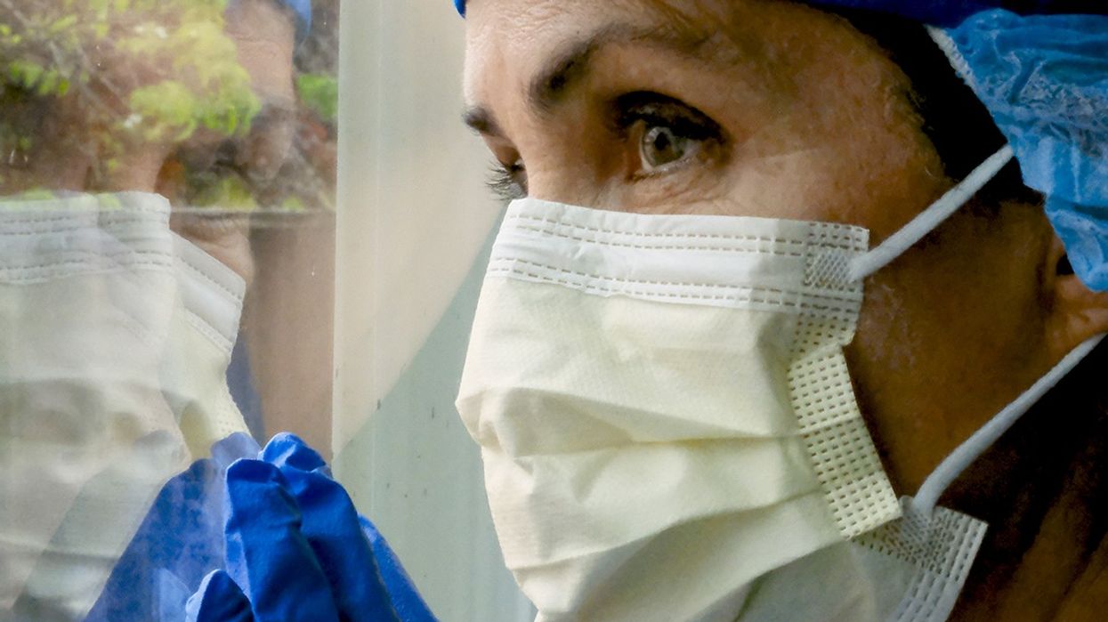 Surgeon in a face mask looking out the window