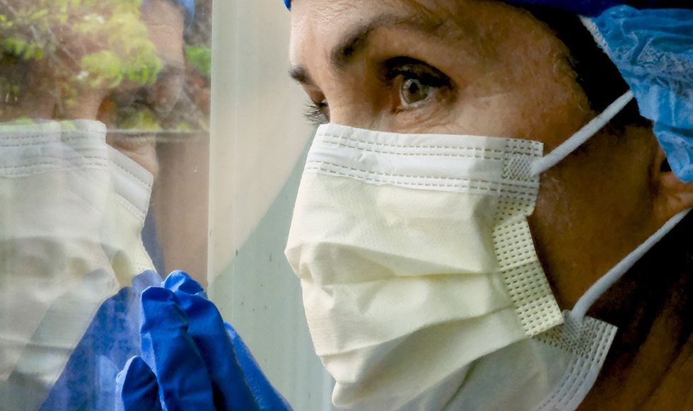 Surgeon in a face mask looking out the window 