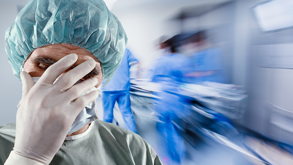 Surgeon with his head in his hands in a busy hospital corridor