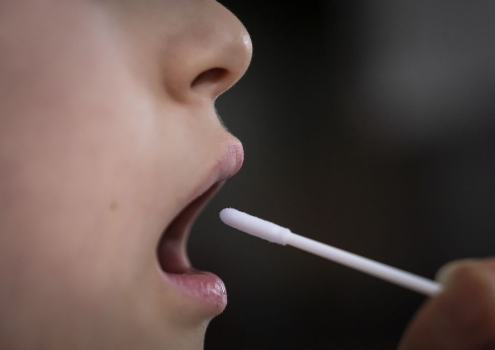 Swab is inserted into a mouth as part of the typical Covid test.