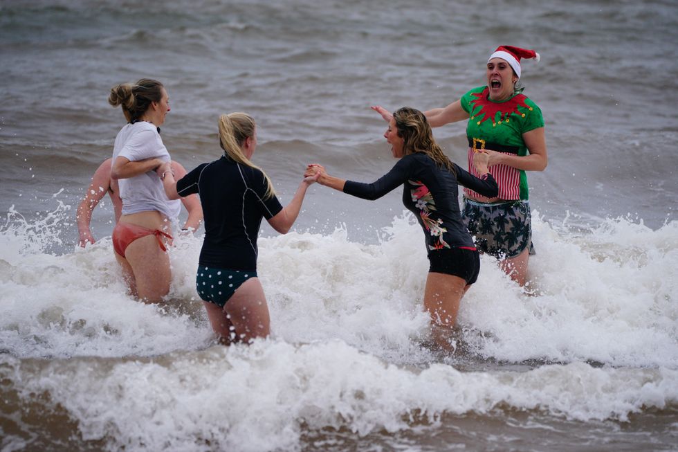 Swimmers in fancy dress take part in a Christmas Day dip at Exmouth, Devon. Picture date: Saturday December 25, 2021.
