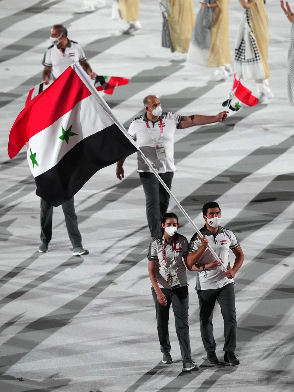 Syrian Arab Republic flagbearers Hend Zaza and Ahmad Saber Hamcho lead out their team.