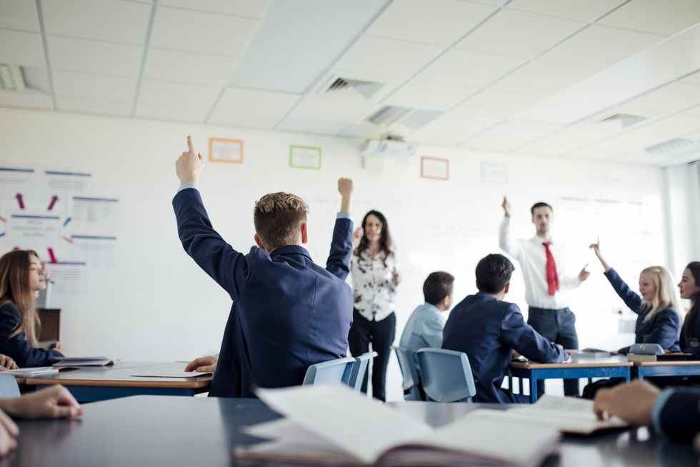 Teenage female student raising her hand to answer a question