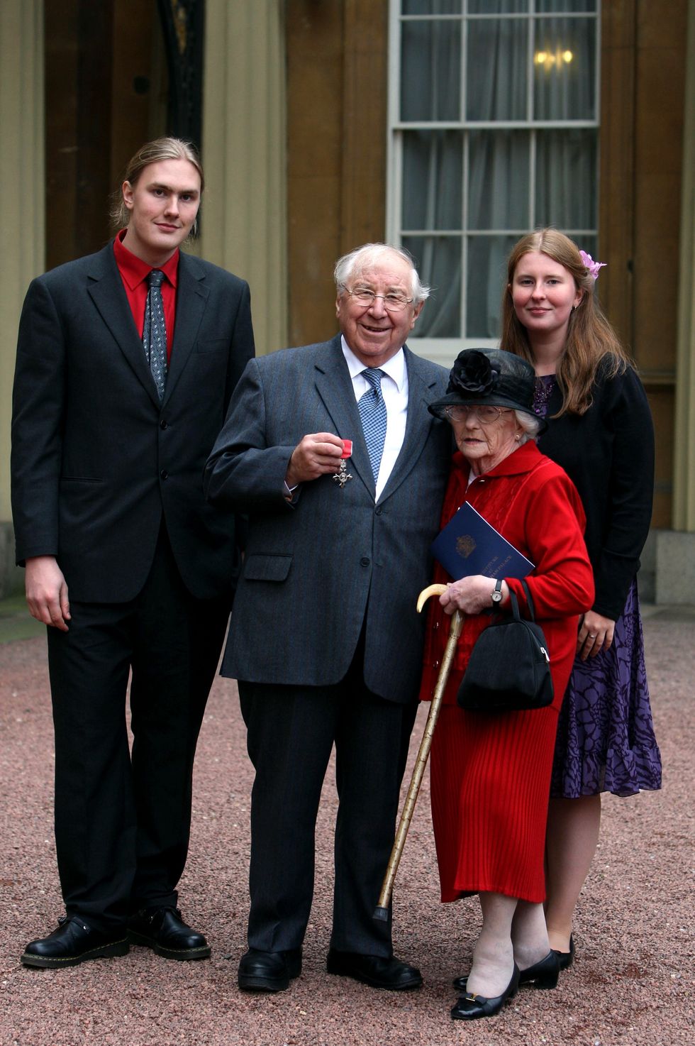 Television presenter Henry Sandon poses with wife Barbara and grandchildren Elizabeth and Robert after receiving his MBE at Buckingham Palace, London.