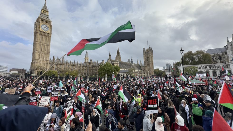 Tens of thousands of pro-Palestinian demonstrators, holding Palestinian flags and banners, gather to hold a pro-Palestinian demonstration at the Parliament Square in central London