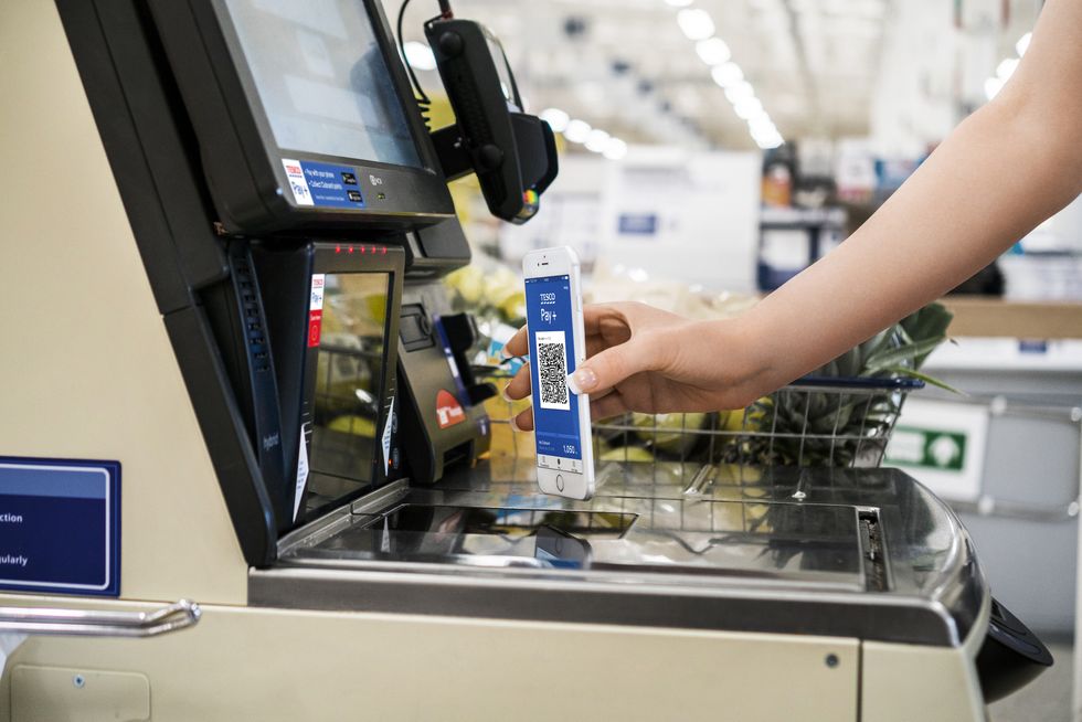 Tesco shopper presents Clubcard at self-service machine