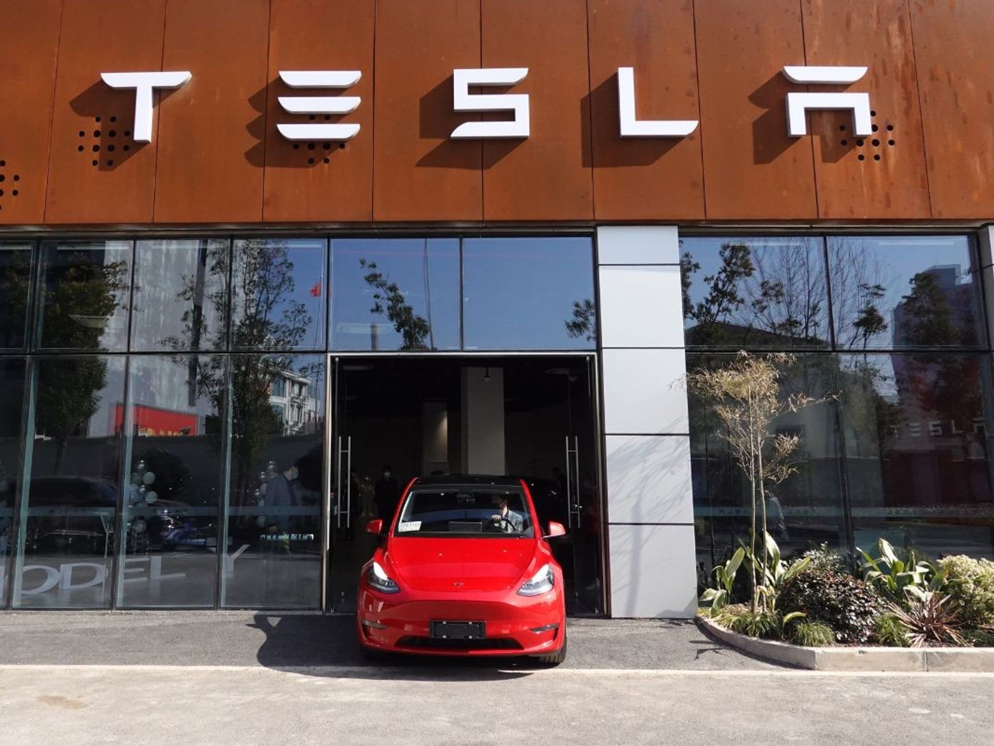 Tesla Model Y drives out of a Tesla dealership