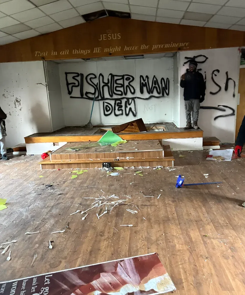 The damaged church hall with debris and rubbish everywhere with graffiti on the walls