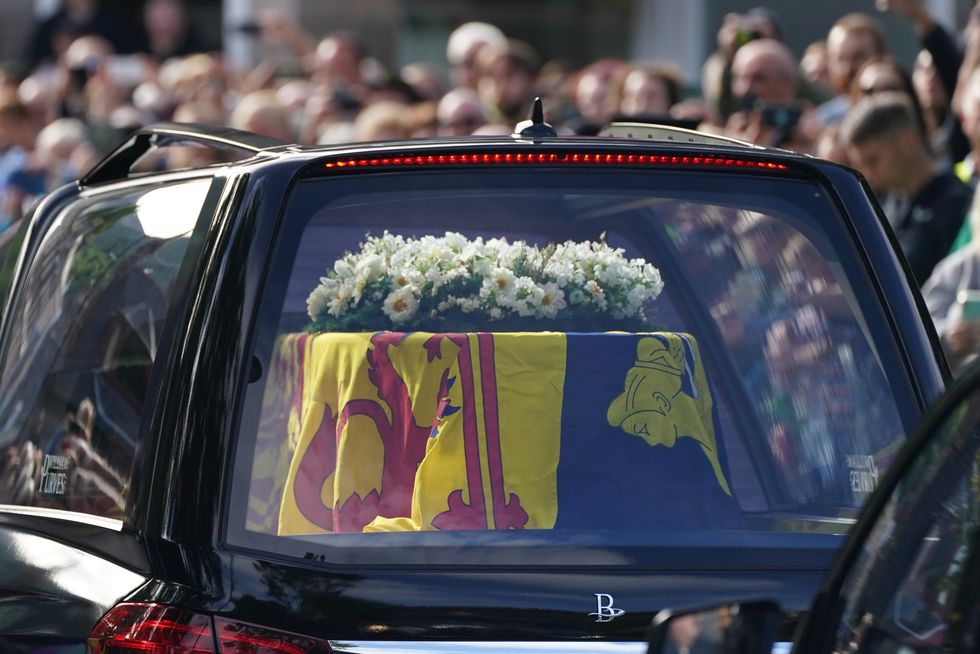The hearse carrying the coffin of Queen Elizabeth II, draped with the Royal Standard of Scotland, passing through Ballater as it continues its journey to Edinburgh from Balmoral. Picture date: Sunday September 11, 2022.