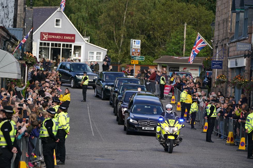 The hearse carrying the coffin of Queen Elizabeth II, draped with the Royal Standard of Scotland, passing through Ballater as it continues its journey to Edinburgh from Balmoral. Picture date: Sunday September 11, 2022.