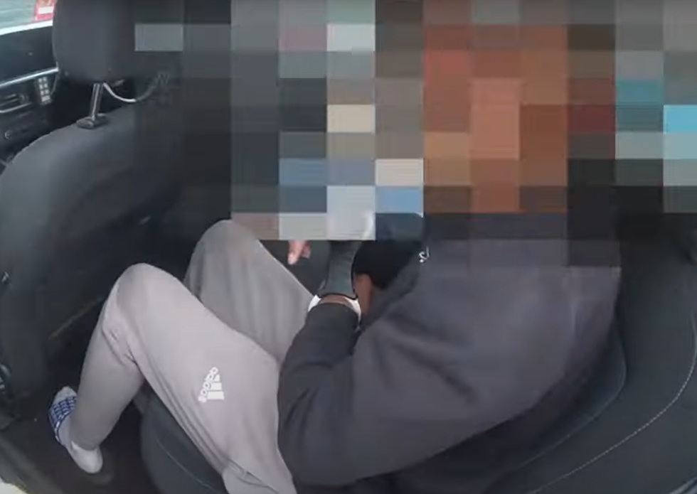 The man being placed in the back of a police car