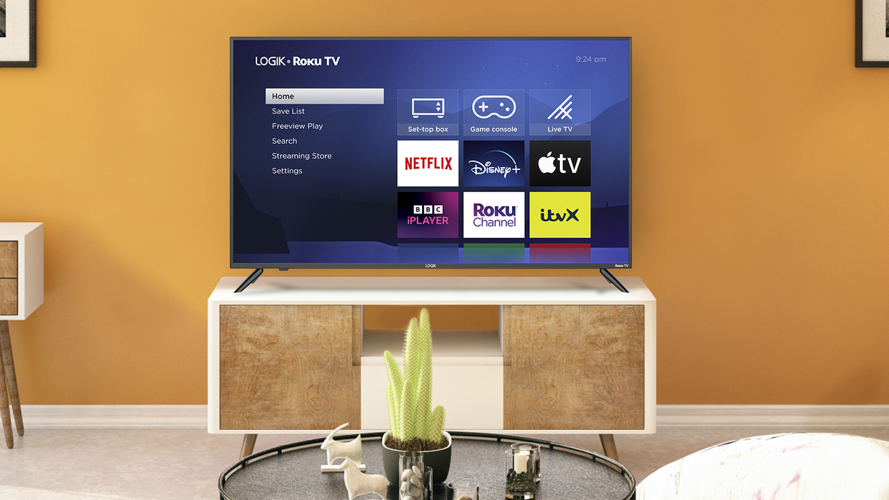the new logik branded smart tv with roku is pictured against an orange wall on a media unit