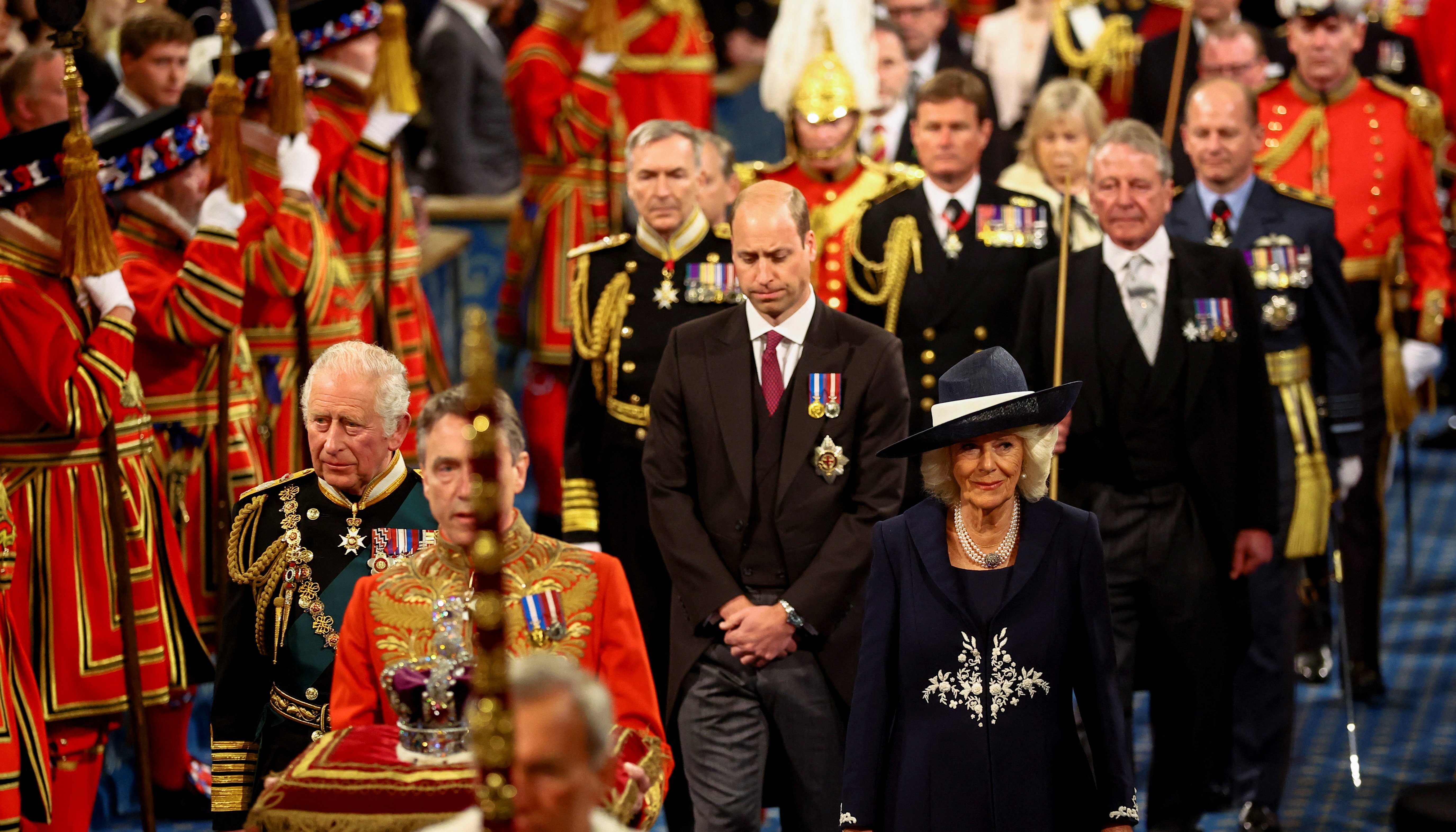 The Prince of Wales and the Duchess of Cornwall with the Duke of Cambridge proceed behind the Imperial State Crown through the Royal Gallery during the State Opening of Parliament in the House of Lords
