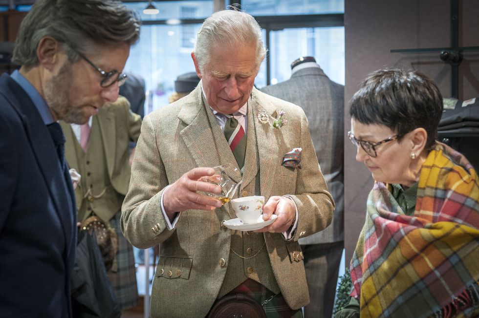 The Prince of Wales, known as the Duke of Rothesay when in Scotland, pours some whisky into his cup of tea at Gibbs Gentlemen's Outfitters during a visit to Inverurie Farmers Market and local shops around the town centre in Inverurie, Aberdeenshire.