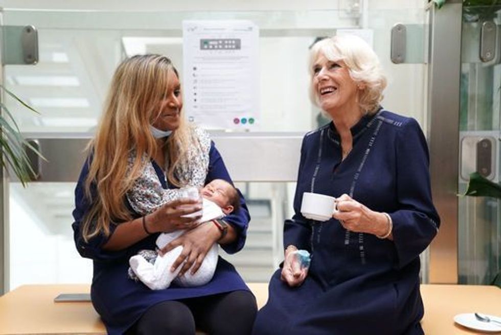 The Queen Consort (right) talks to SafeLives pioneer Shana Begum and her 3-week-old baby, Jeremy, during a visit to a maternity unit at Chelsea and Westminster hospital in London