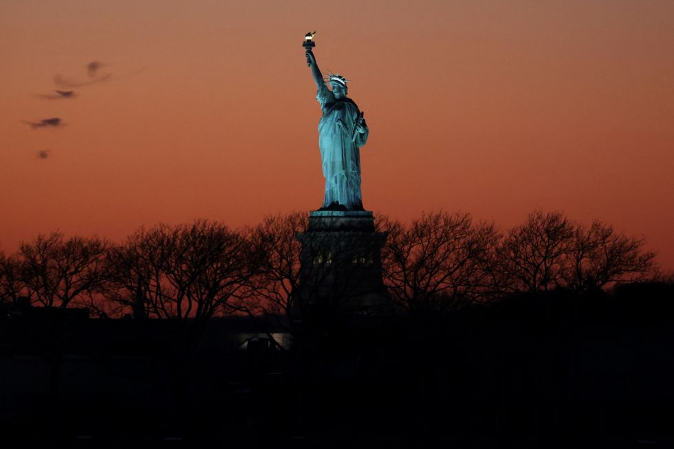 The Statue of Liberty is seen at sunset in New York City, U.S., December 20, 2021. REUTERS/Andrew Kelly