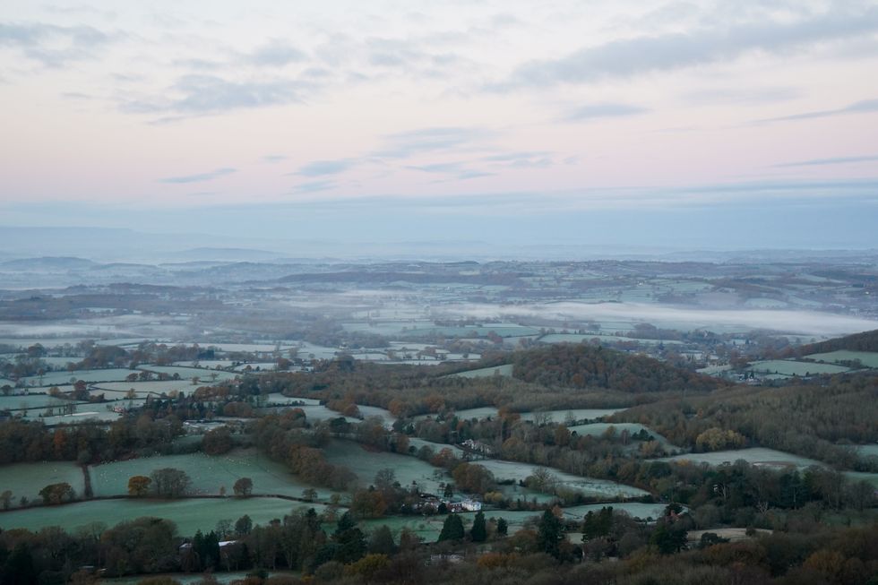 The sun rises over a foggy Worcestershire as seen from the Malvern Hills.