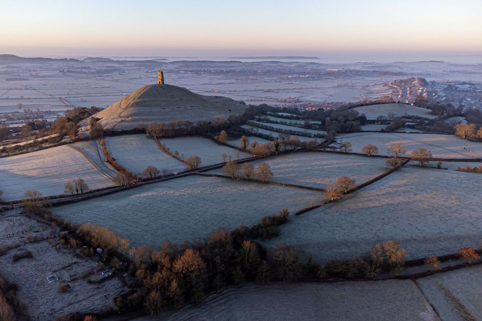 The sun rises over the Somerset Levels and strikes fields around Glastonbury Tor