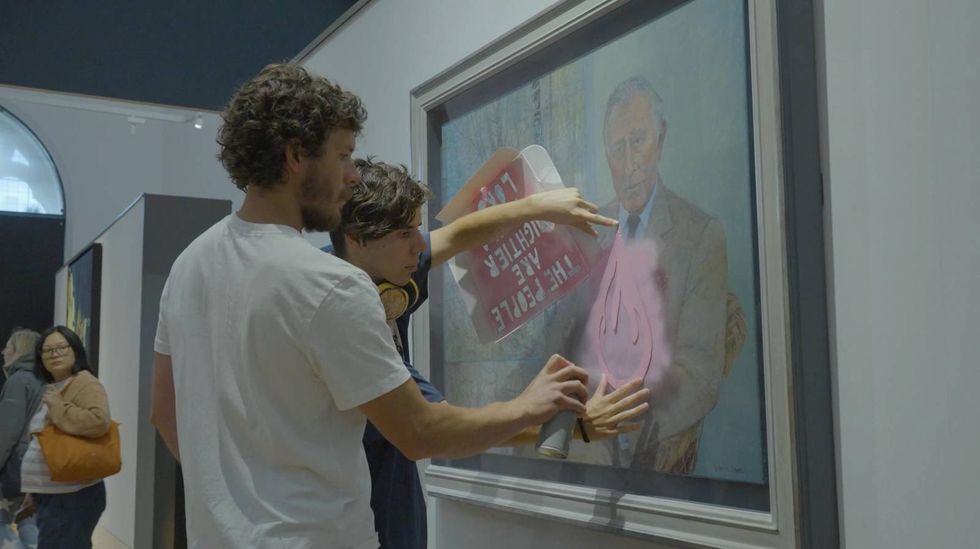 The two activists spray paint the King Charles portrait