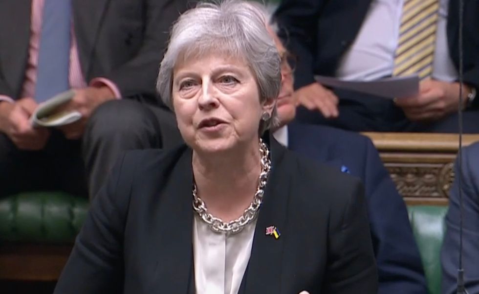 Theresa May speaking to Priti Patel in the House of Commons