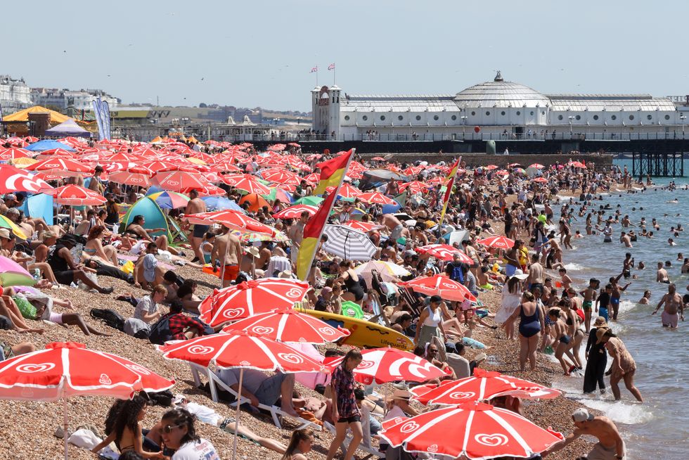 Thousands of sun-seekers seen under umbrellas enjoy the Brighton coast as the heatwave continues