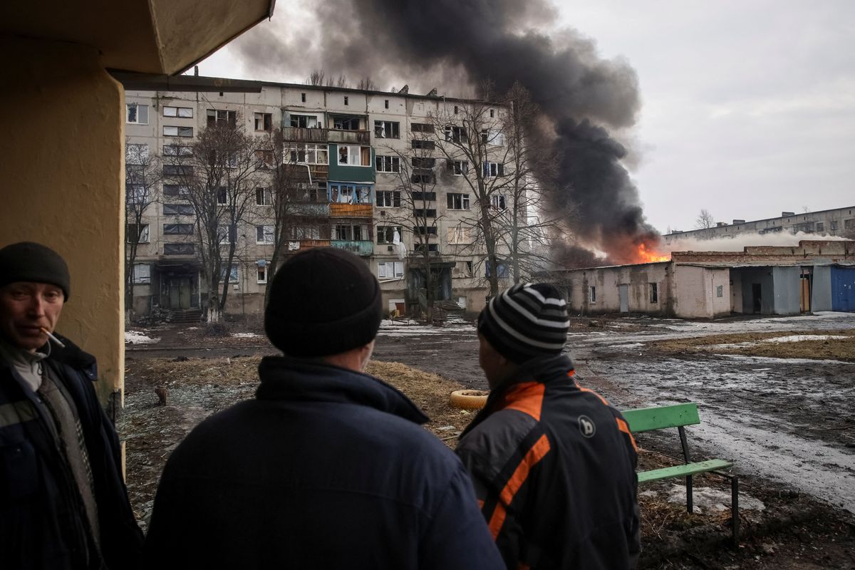 Three men watching an explosion in Ukraine